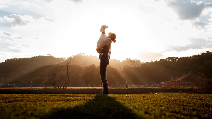 Girl holding a dog at sunset.