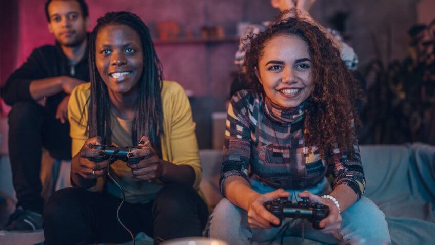 Group of multi ethnic people, friends sitting at home, playing video games.
