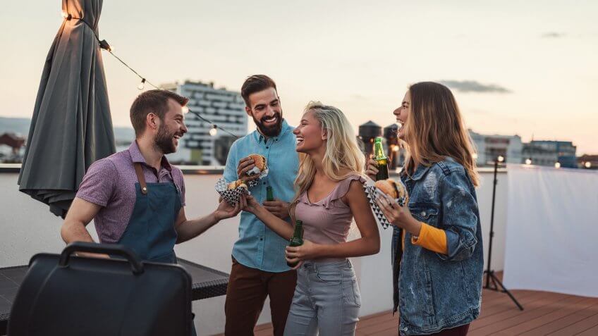 Cropped shot of four friends having fun while making barbecue on a rooftop.