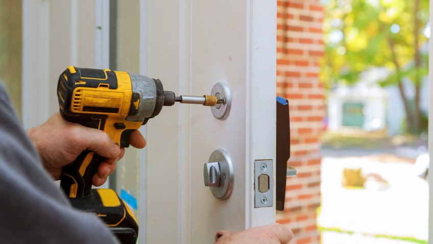 worker's hands installing new door locker man repairing the doorknob.