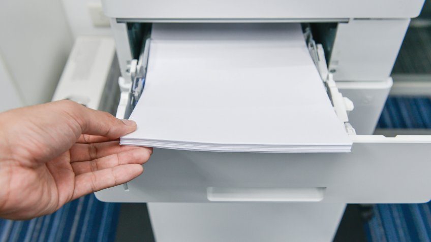 Human hand is reloading the paper to printer tray.