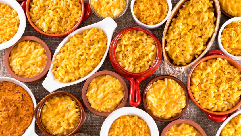 Several bowls filled with different types of cheese macaroni served on cotton table cloth.
