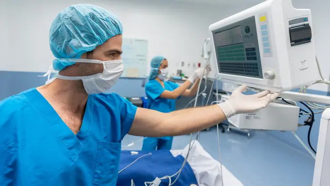 Portrait of a doctor in surgery checking the vitals of a patient - healthcare and medicine concepts.