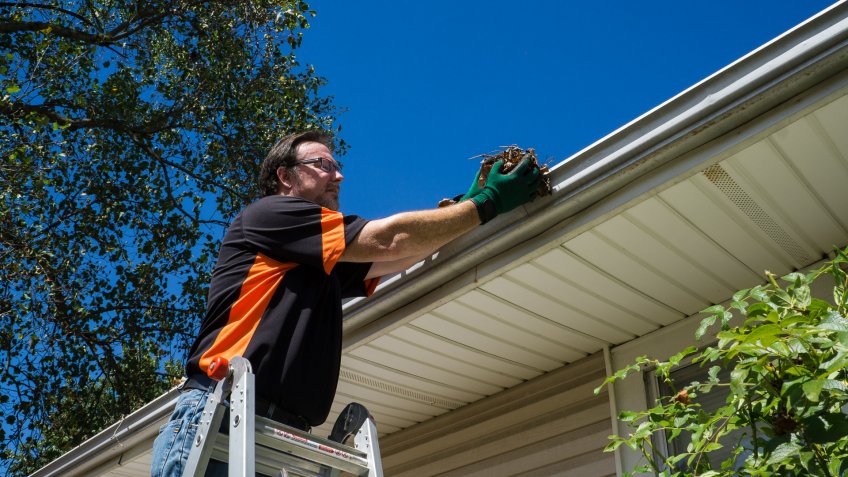 Worker cleaning gutters on a customers home.