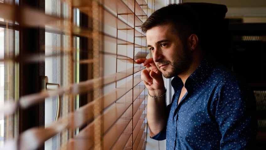 Man looking through a jalousie.