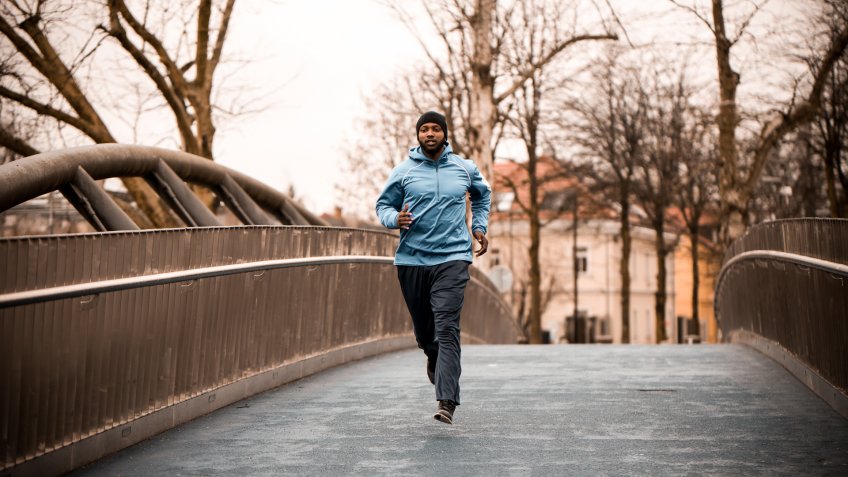 Waist down image of a man running over the concrete bridge.