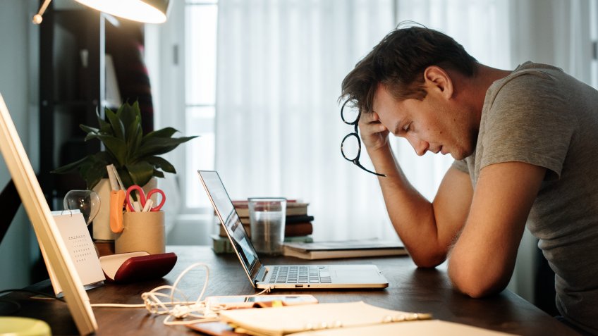 Man stressed while working on laptop.