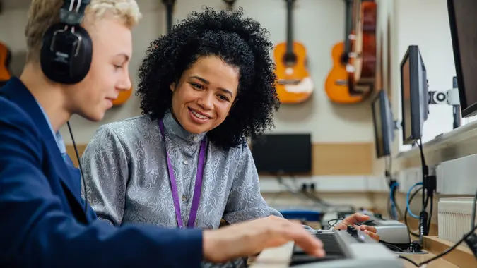 Female teacher is sitting with one of her students in a music lesson at school.