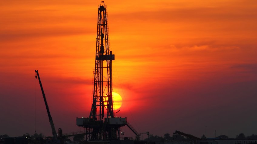 Sunset at oil drilling rig in the field.