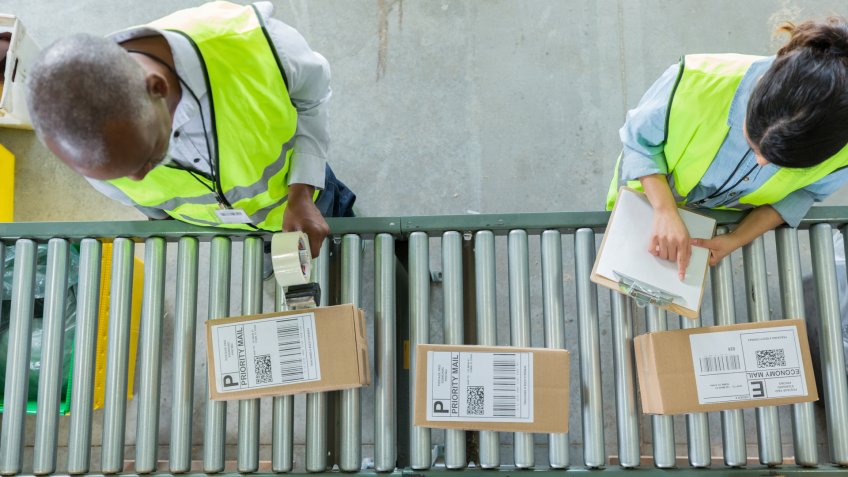Male and female distribution warehouse employees process customers' orders.