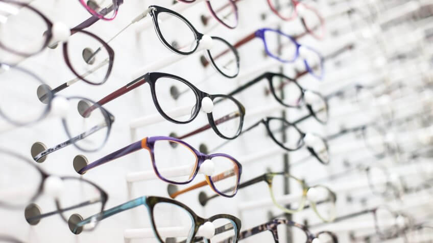 Large group of eyeglasses in an eyewear store display.