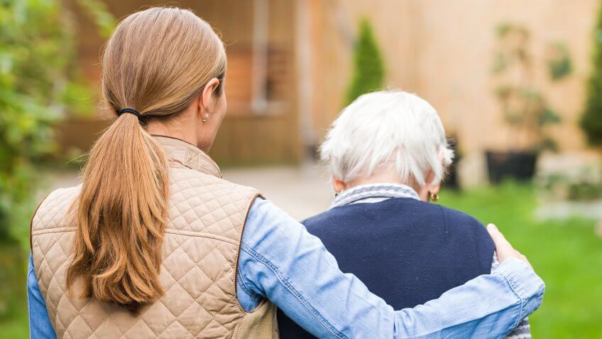 Young carer walking with the elderly woman in the park.