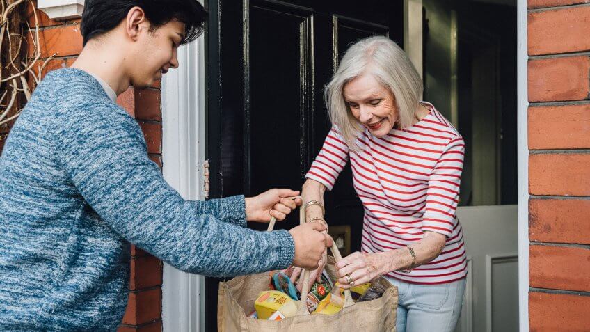 Teenage boy is delivering some groceries to an elderly woman.