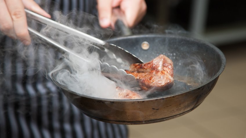 Hands chef cooking lamb.