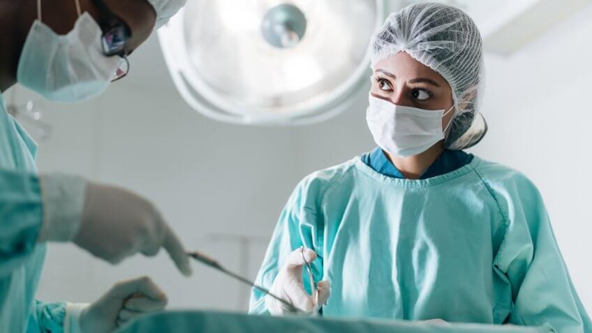 Two female doctors using surgical scissors in the operation room.