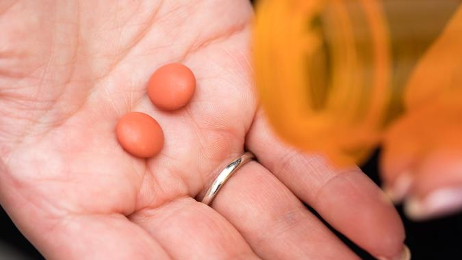 Two Ibuprofen pills spilling out of bottle.