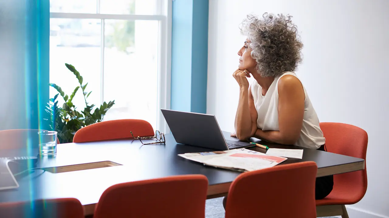 Middle aged woman looking out of the window in the boardroom.