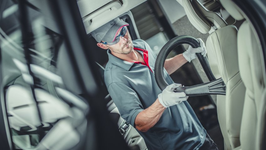 Modern Car Interior Vacuuming by Professional Caucasian Worker.