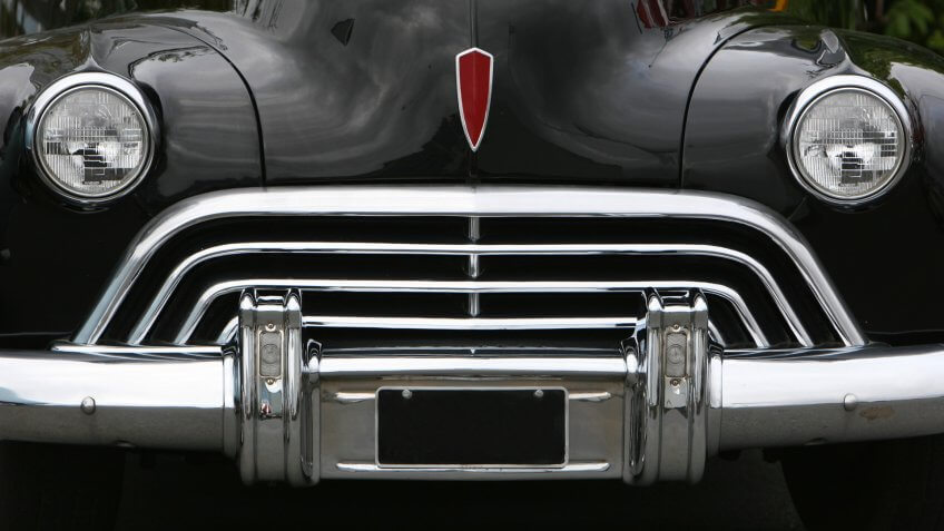 photograph of an old classic car in mint condition, shining chrome and highly polished finish , almost like a face with mouth eyes and nose.