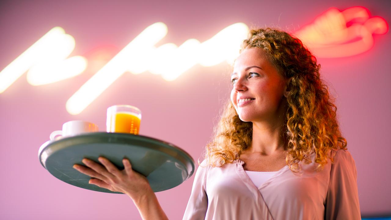 Cheerful attractive curly-haired waitress holding tray and looking aside while working at night bar - Image.