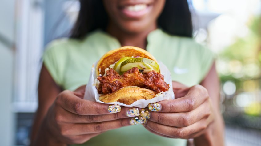 african american woman holding fast food style crispy fried chicken sandwich shot wit selective focus.