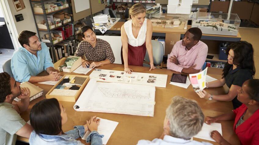 Female Boss Leading Meeting Of Architects Sitting At Table - Image.
