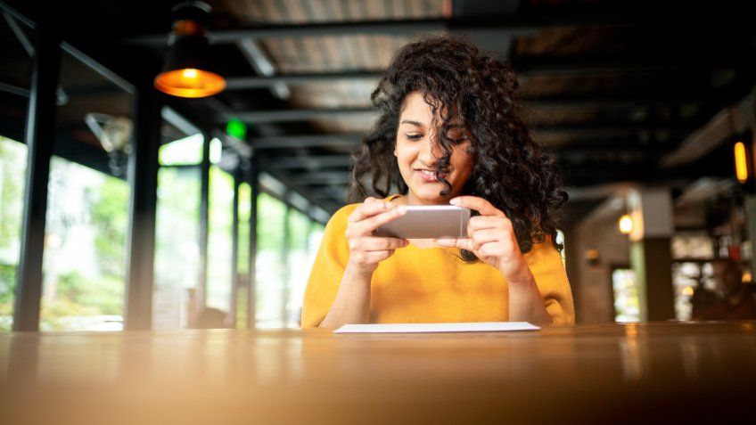 Young Indian woman making a photo of a check at the bar.