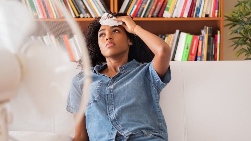 Black woman sweating and trying to refresh at home.