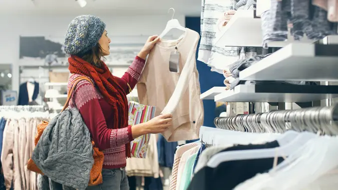 Closeup of smiling blond woman choosing clothes at department store in local supermarket.