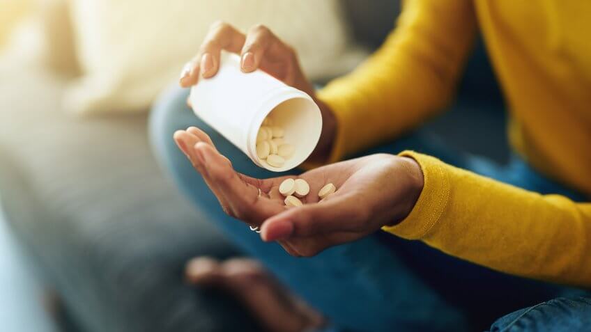 Cropped shot of a young woman taking medication at home.