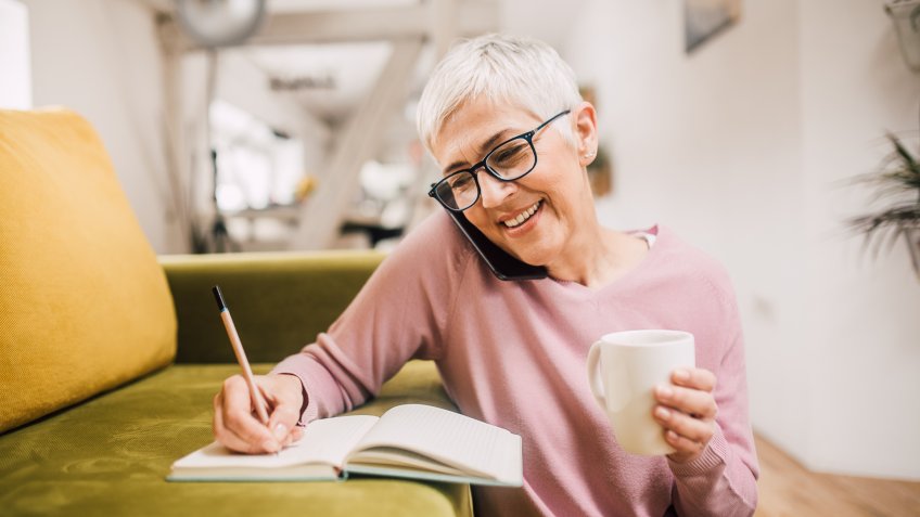 Woman talking on mobile phone and writing.