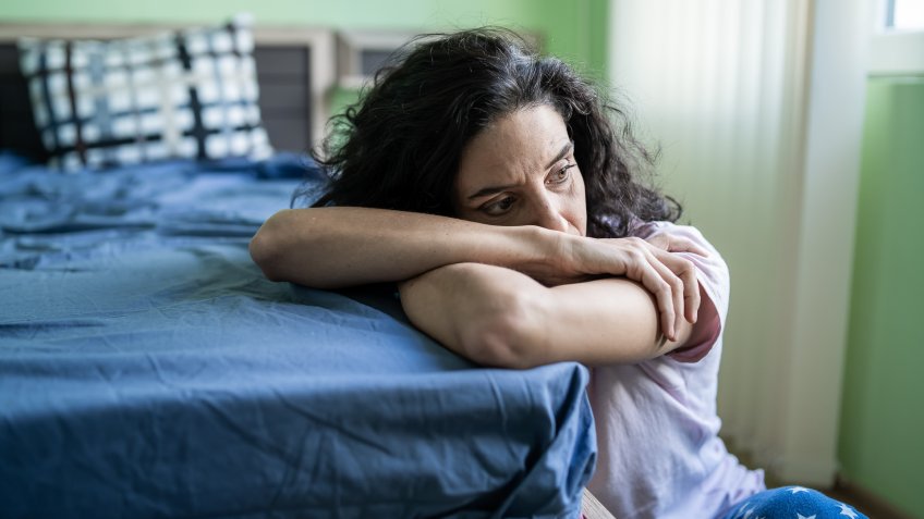 Mid adult woman sitting home alone, worried.