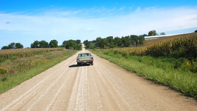 An old car going down a country road in rural Warren County, Iowa.