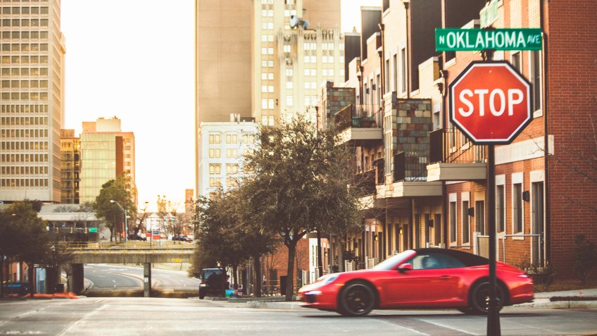 Oklahoma City, USA - February 19, 2014: Red sports car driving on empty downtown streets during sunset time.