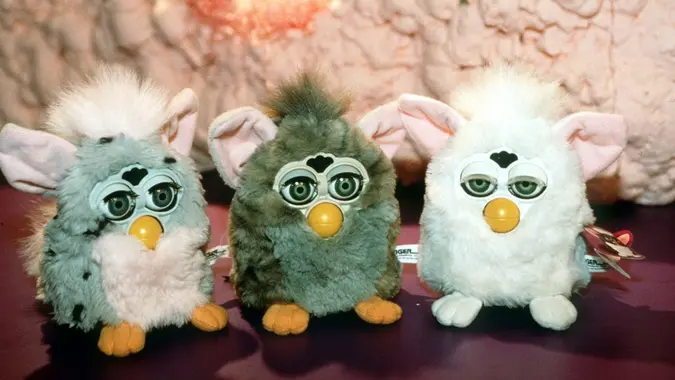 Three Furby toys lined up. One is grey, one light brown and one white.