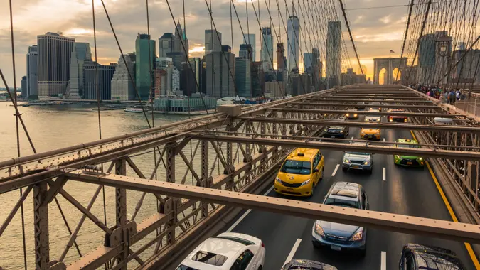 Traffic on Brooklyn Bridge at sunset with Manhattan skyline in the background (New York, USA).