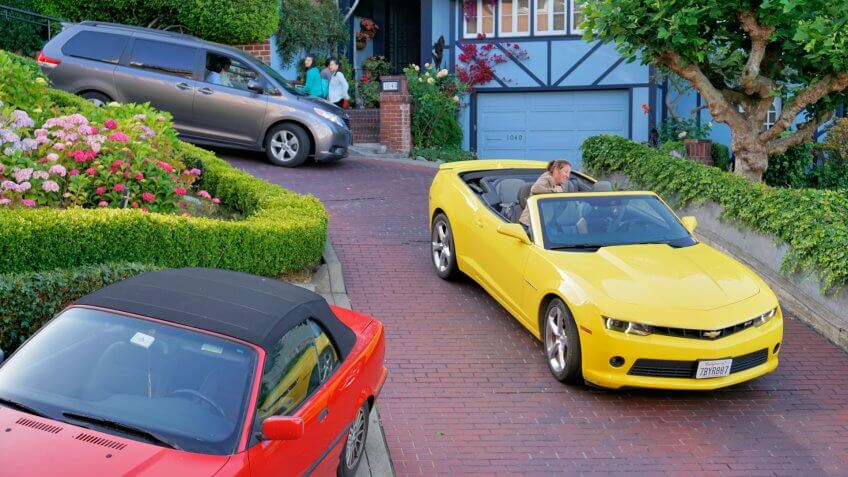 San Francisco, USA - May 29, 2014: Pedestrians and people in cars on the steep and winding Lombard Street in California, a popular tourist spot.