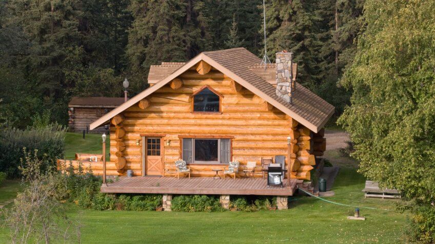 A log home alongside a river in Alaska - Image.