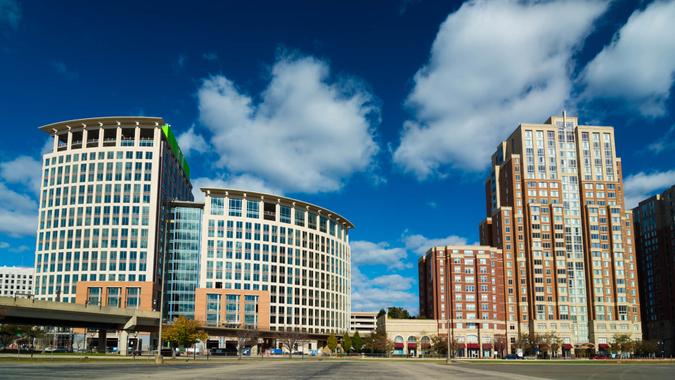 An office highrise building (left) and a highrise residential building (right) in Alexandria’s Carlyle neighborhood, with dramatic clouds in the background.