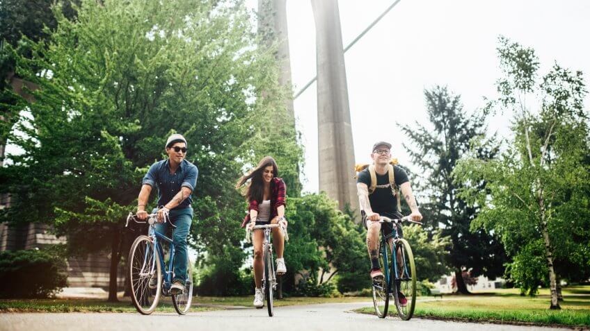A mixed-race group of friends commuting in an urban city environment with trees in background.