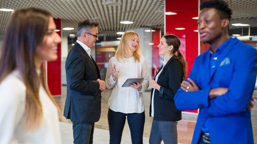 Business people standing and talking in the business center lobby.