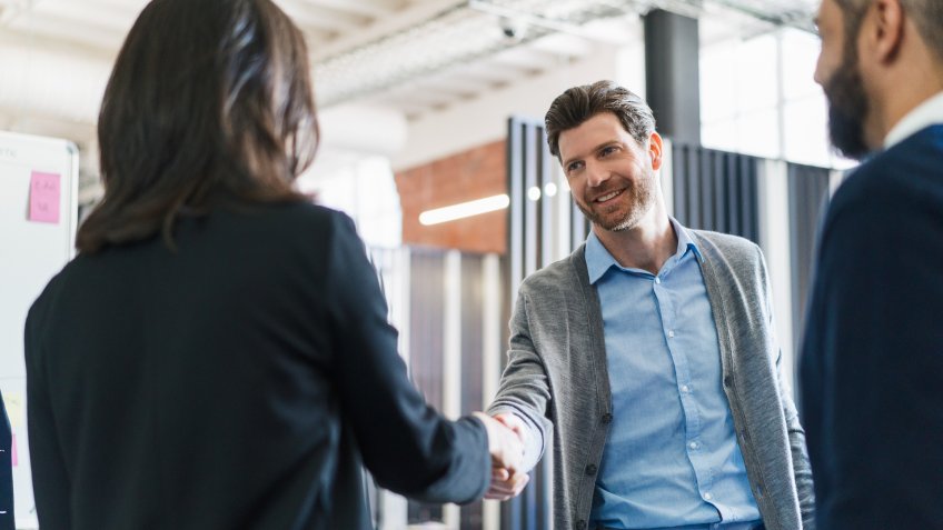 Businessman greeting female colleague at workplace.