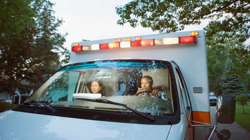 Male and female paramedics in cab of ambulance.