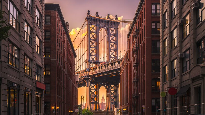 Manhattan bridge seen from a brick buildings in Brooklyn street in perspective, New York, USA.