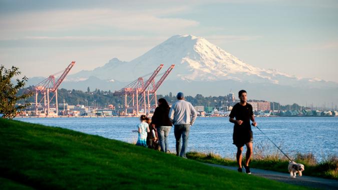 Seattle, USA - October 5, 2013: A family and a man jogging with his dog just before sunset in Myrtle Edwards Park with a view of Mount Rainier.