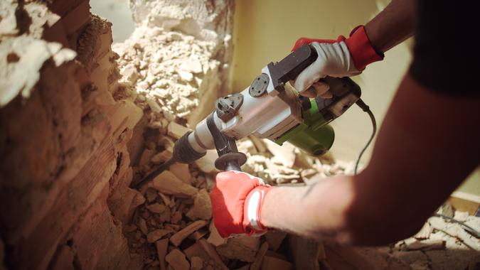 Home Renovation, Builder with hammer breaking wall indoors Home Renovation, Builder with hammer breaking wall indoors.