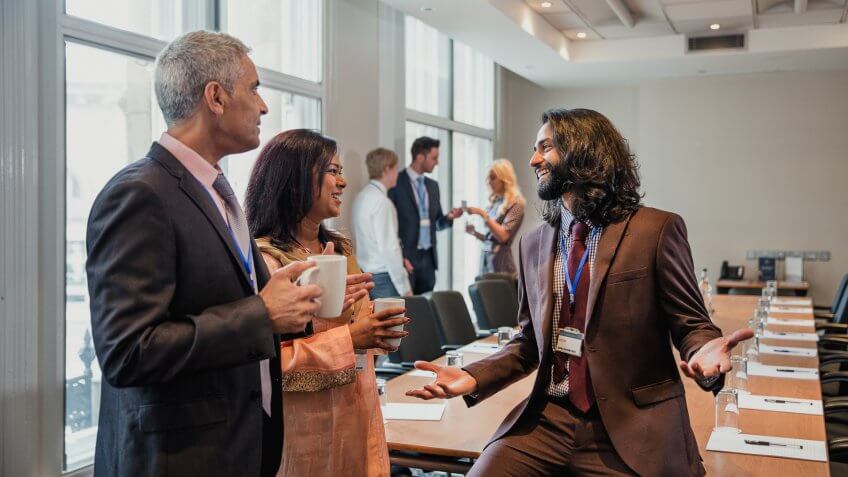 Small group of business men and women talking before a conference.