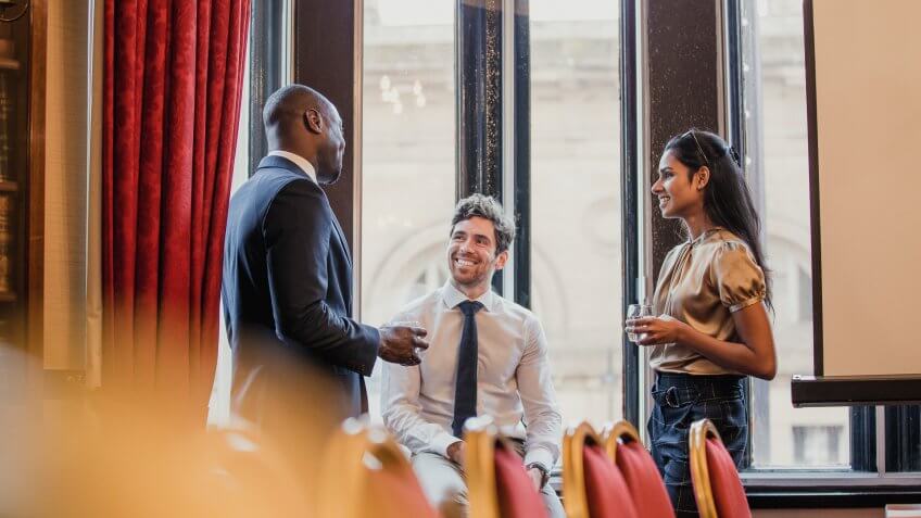 Side view of three business people, standing, talking after a business conference.