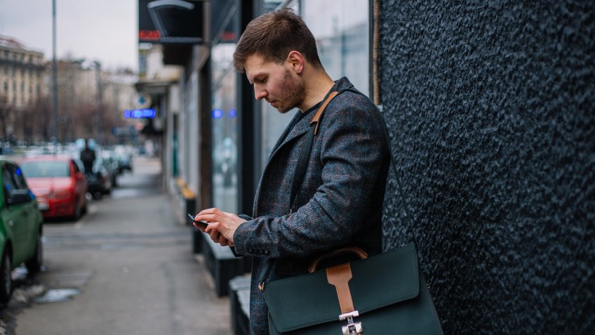 Young businessman performs its economic business, sitting or standing with a cup of coffee in hand.