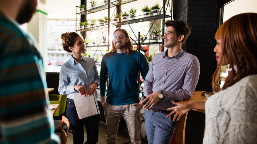 Young smiling businessman talking with his coworkers in the office.